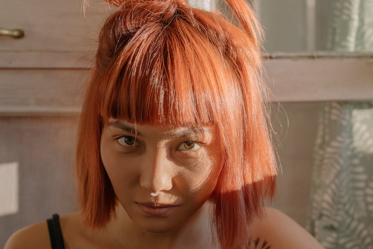 home-hero Close-up portrait of a woman with vibrant red hair illuminated by natural sunlight. Indoors setting.